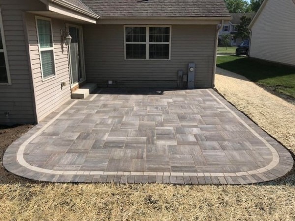 J.T. & Sons Lawn Care team member installing a concrete paver patio for a homeowner in the Bloomington-Normal, IL community.